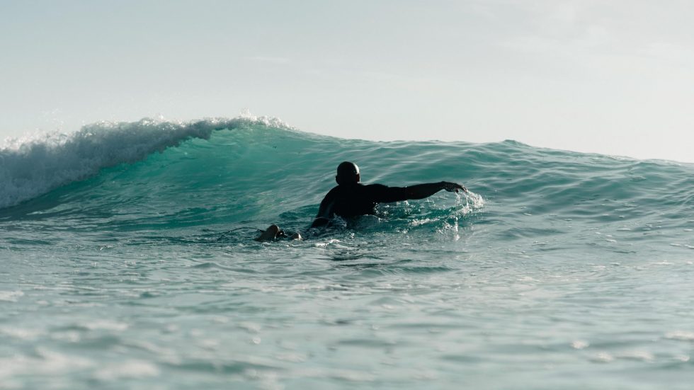 Surfer paddling over wave